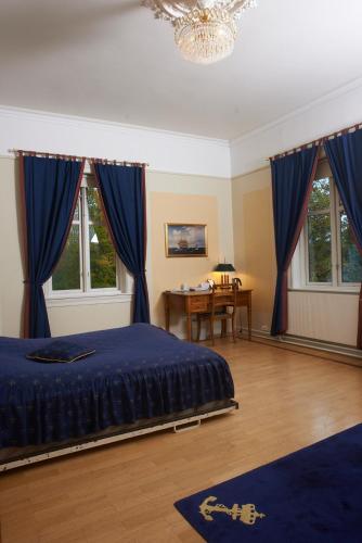 a bedroom with blue curtains and a table and a bed at Sjømilitære Samfund in Horten