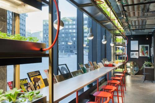 a bar with orange stools and a large window at Hobo Hotel Stockholm in Stockholm