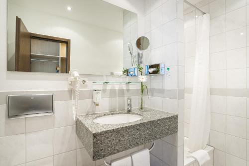 a white bathroom with a sink and a mirror at Novum Hotel Mariella Airport in Cologne