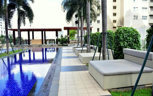 una piscina con sillas y palmeras junto a un edificio en SkyLounge Apartment 2 Colombo en Colombo