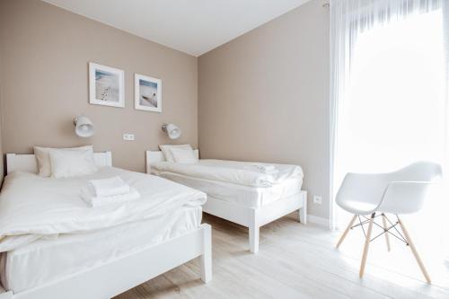 biała sypialnia z 2 łóżkami i krzesłem w obiekcie Apartment No. 1 - Vento Apartamenty we Władysławowie