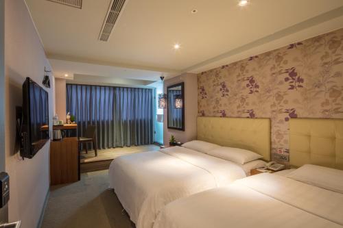 a hotel room with two beds and a television at Urtrip Hotel in Taipei