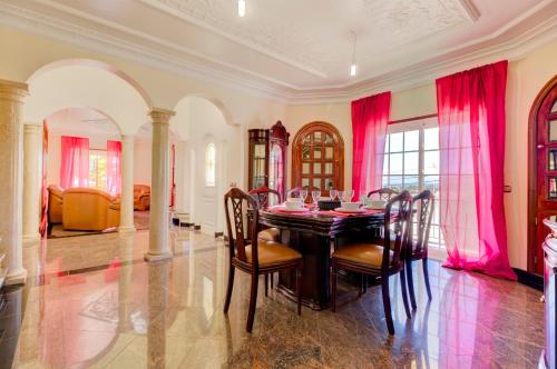 a dining room with a table and chairs and pink curtains at Villa Menir in Lagoa