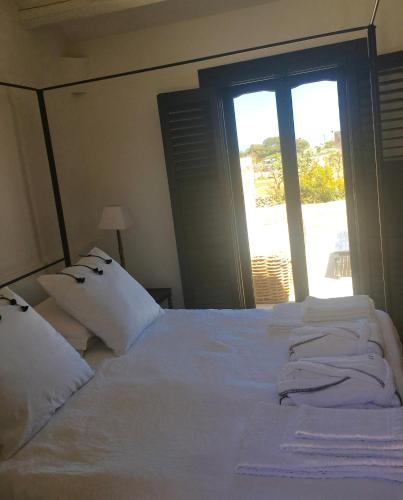 a large white bed with white pillows and a window at Il Baglio sull'Acqua in Favignana