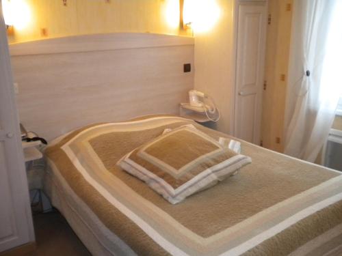 ein Schlafzimmer mit einem Bett mit zwei Kissen darauf in der Unterkunft Hotel Restaurant A l'Ange in Climbach