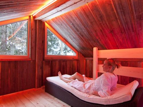 a woman laying on a bed in a room with windows at Gasthof Hochsteg in Finkenberg
