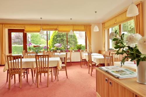 un comedor con mesas, sillas y ventanas en Hotel Reineldis en Mureck