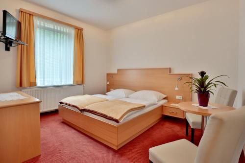 a bedroom with a bed and a desk and a table at Hotel Reineldis in Mureck