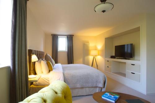 um quarto de hotel com uma cama e uma televisão em The Plume of Feathers em Mitchell