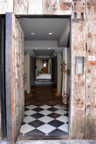 an open door to a hallway with a checkered floor at Las Glicinas Boutique Apartments in Colonia del Sacramento