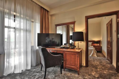 a hotel room with a desk with a television at Grand Hotel Stamary in Zakopane