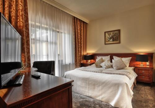 a hotel room with a bed and a television at Grand Hotel Stamary in Zakopane