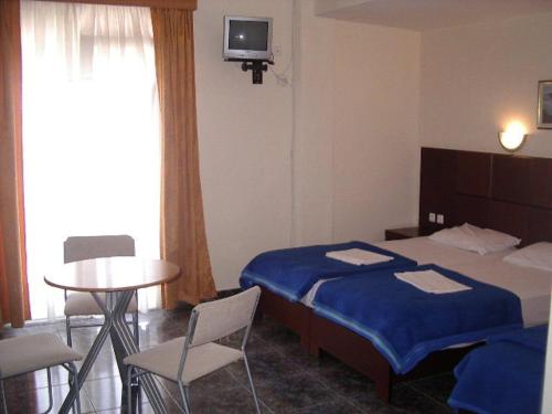 a hotel room with a bed and a table and chairs at Hotel Dias Apartment in Makrýgialos