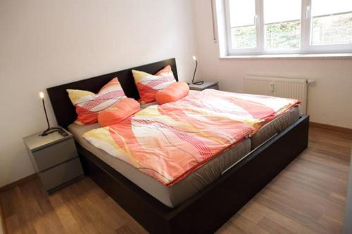 um quarto com uma cama com lençóis e almofadas laranja em Traumwohnung am Altstadtrand em Regensburg