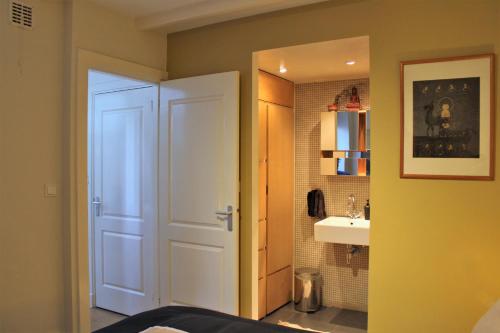 ein Badezimmer mit einer weißen Tür und einem Waschbecken in der Unterkunft Amsterdam Lily apartment in Amsterdam