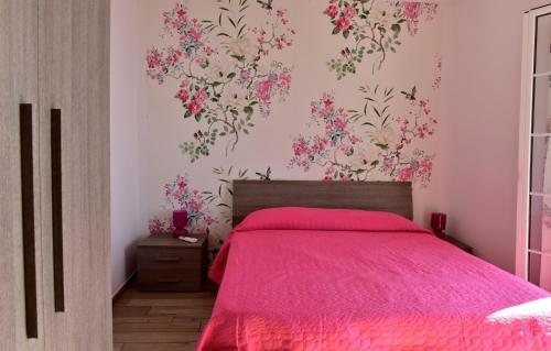 a bedroom with a pink bed with flowers on the wall at Agriturismo Un Mare di Fiori in Ventimiglia
