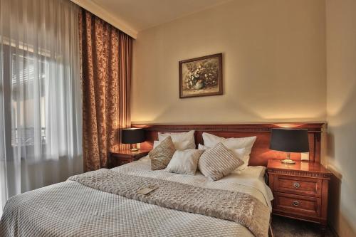 a bedroom with a bed with two lamps and a window at Grand Hotel Stamary in Zakopane