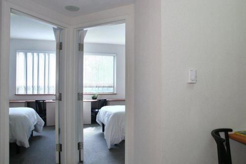 een kamer met 2 bedden en een hal met een spiegel bij Residence & Conference Centre - Oakville in Oakville