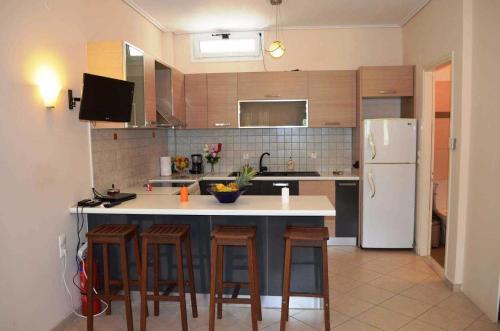 a kitchen with a island with bar stools and a refrigerator at Rania Apartments in Agios Nikitas