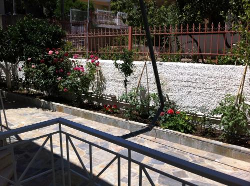 a swing in a garden with flowers and a fence at Erato Apartments in Petalidhion