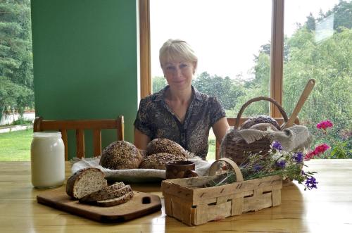 a woman sitting at a table with bread at Forest B&B in Krāslava