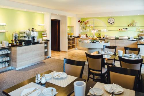 a restaurant with tables and chairs and a kitchen at Hotel Astoria Bonn in Bonn