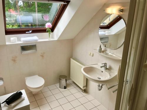 a bathroom with a sink and a toilet and a window at Lokal Genial Pension & Restaurant in Beelitz