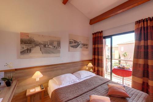a bedroom with a bed and a large window at Hotel Le Phoebus Garden & Spa in Gruissan