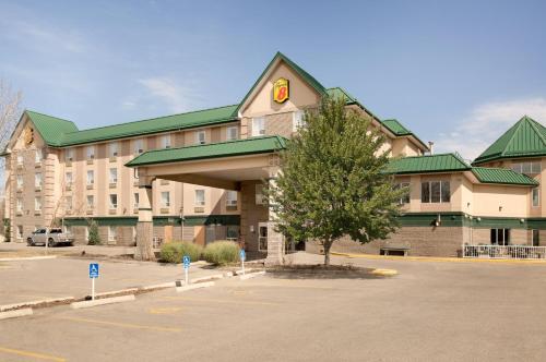 un grand bâtiment avec un arbre dans un parking dans l'établissement Super 8 by Wyndham Calgary Shawnessy Area, à Calgary