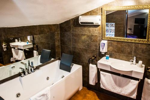 y baño con bañera, lavabo y espejo. en La Posada De La Magistral en Alcalá de Henares