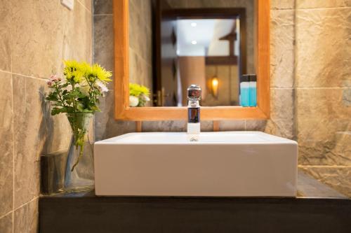 a bathroom sink with a mirror and a vase of flowers at 夕露小榭古城南门店 Xilu Xiaoxie Inn Old Town Lijiang in Lijiang