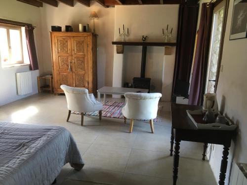 a bedroom with a bed and two chairs and a table at La Troliere in Autry-Issards