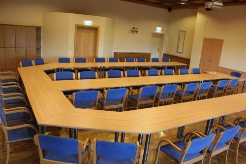 a large room with rows of tables and blue chairs at Vitalhotel Marienhof in Velden am Wörthersee
