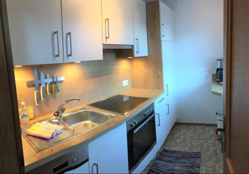 a kitchen with white cabinets and a sink at Appartement Alpenhof Wildschönau in Niederau