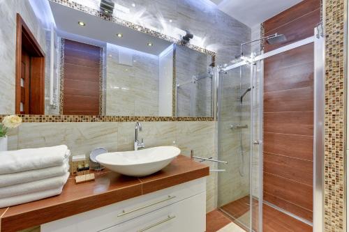 a bathroom with a sink and a glass shower at INA Rent - Tre Mare Apartamenty in Gdańsk