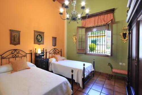 a bedroom with two beds and a window and a chandelier at Villa 'Los Balcones' in Priego de Córdoba
