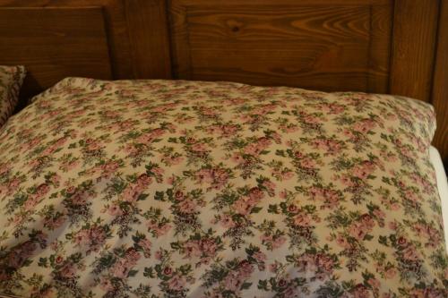 a bed with a floral bedspread on it at Penzión Thamasy in Spišské Tomášovce