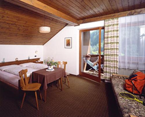 a bedroom with a bed and a table and a window at Hotel Bad Bergfall in Valdaora