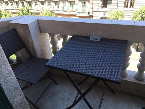 un banco y dos sillas sentados en un balcón en All In Apartman III., en Budapest