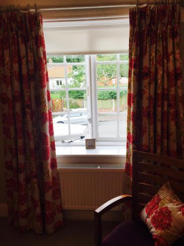 a window with curtains and a chair in a room at The White Horse in Overstrand