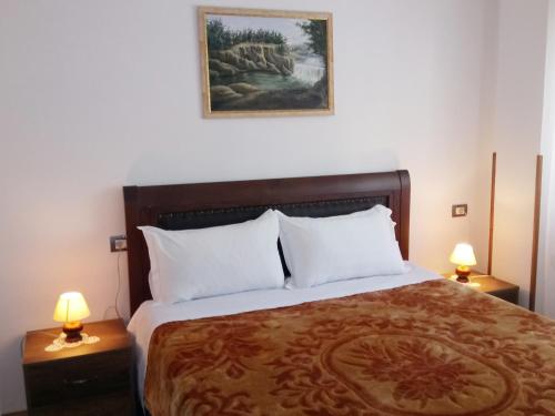 a bedroom with a large bed with two lamps at Guesthouse Villa Juri in Berat