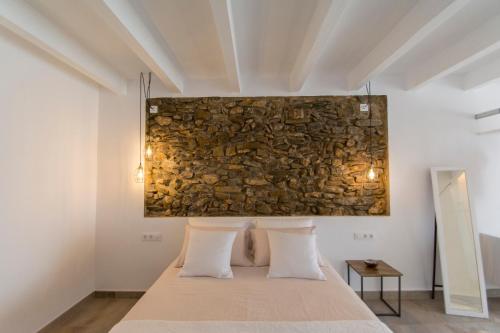 a bedroom with a stone wall above a bed at Agroturismo Son Vives Menorca - Adults Only in Ferreries