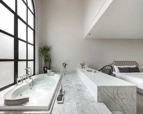 a white bathroom with a tub and a couch at Hotel Once Bangkok in Bangkok