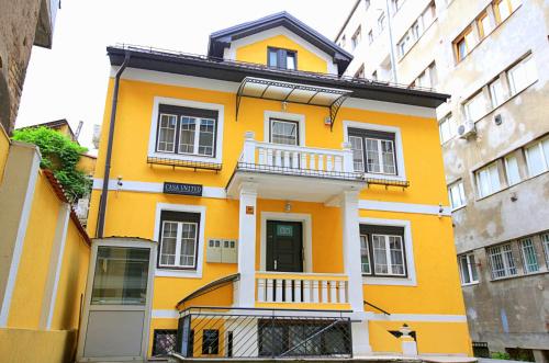 une maison jaune avec un balcon dans une ville dans l'établissement Sarajevo Apartments Casa United, à Sarajevo