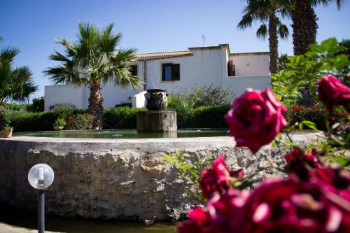 a fountain in front of a house with palm trees at Case Vacanza Torre Lupa in Marsala