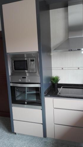 a kitchen with a microwave and a stove at VistaFreita- Rooms & Suites in Arouca