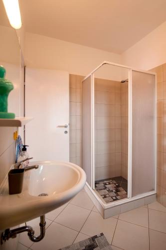 a white bathroom with a shower and a sink at Apartments Roko in Rovinj