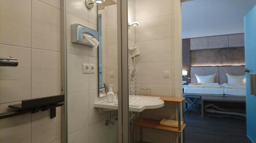 a bathroom with a sink and a mirror and a bed at Flair-Waldhotel Mellestollen in Saalfeld