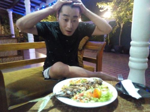 a man sitting on a bench with a plate of food at Yuthika Resort in Negombo