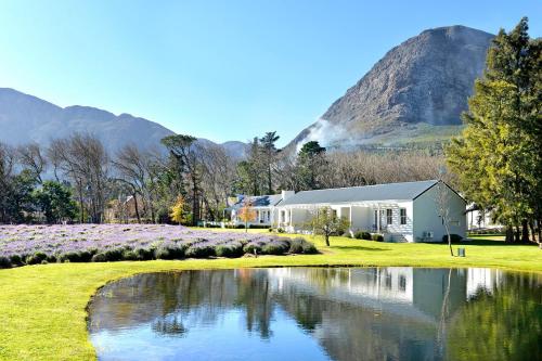 フランシュホークにあるLavender Farm Boutique Guest Houseの山を背景にした池の隣の家